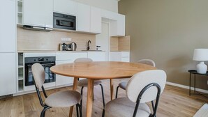 A modern kitchen with white cabinets, a round wooden table, and four chairs. - Blueground | Prague 3, close to offices & mall (PRG-20) (Prague)