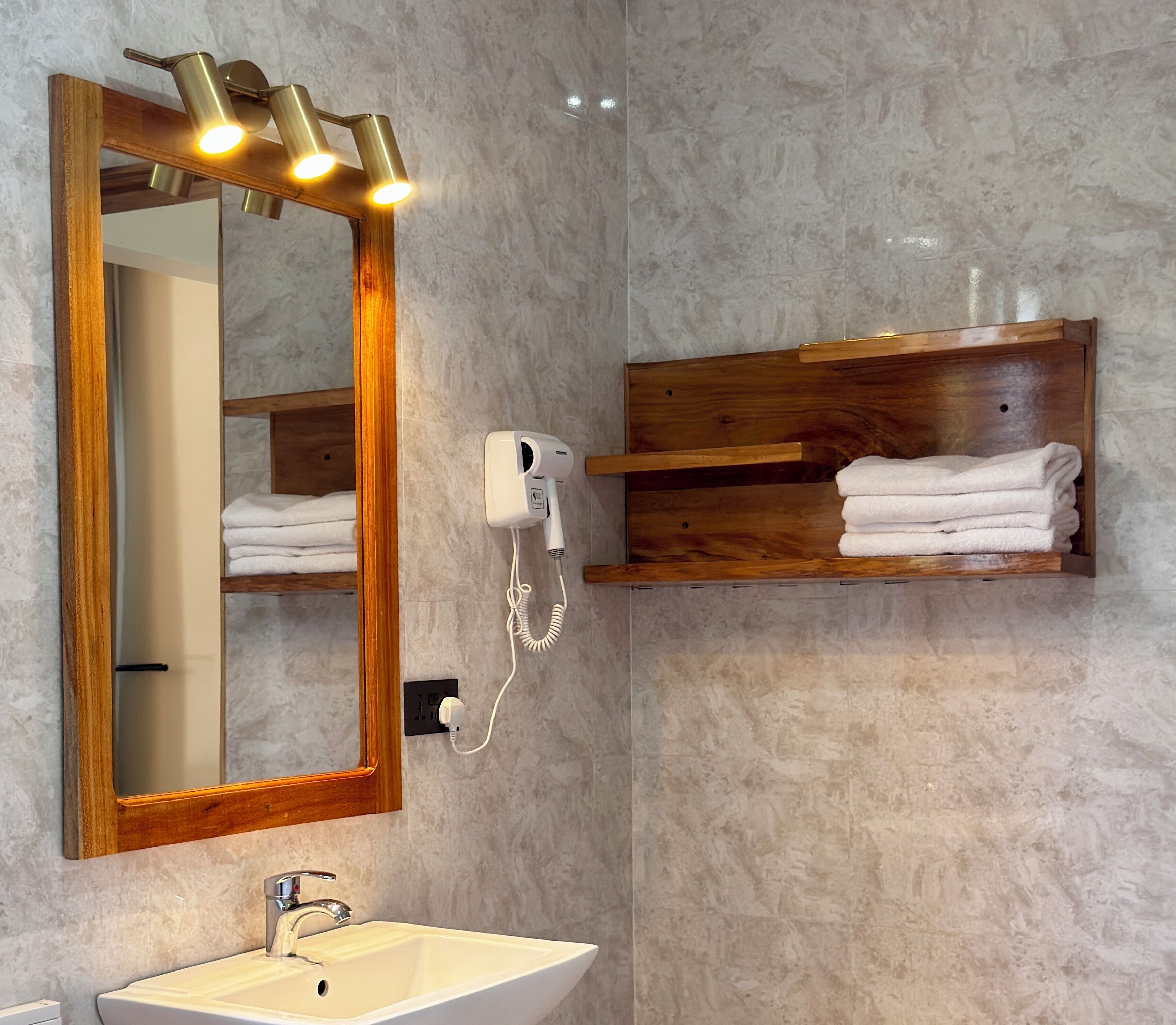 A bathroom with a large mirror, a sink, a towel rack, and a hairdryer.