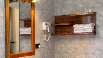A bathroom with a large mirror, a sink, a towel rack, and a hairdryer.