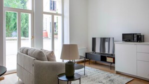 A modern living room with a sofa, a TV, a coffee maker, and a small table.