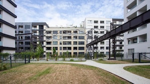 Et moderne boligkompleks med flere bygninger, en central gårdsplads og en fodgængerbro.