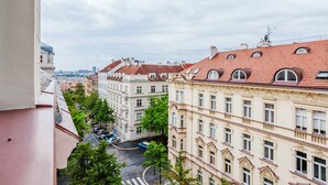 Vista di un paesaggio urbano con edifici dall'architettura classica e una strada con auto parcheggiate.