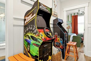 Ein Zimmer mit Spielautomaten, einem Bett, einem Stuhl und einem Fenster.