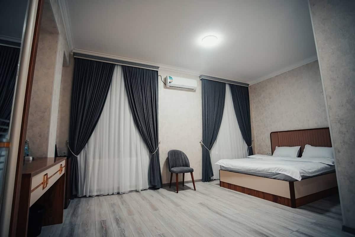 Een hotelkamer met een bed, een stoel, een bureau en gordijnen.