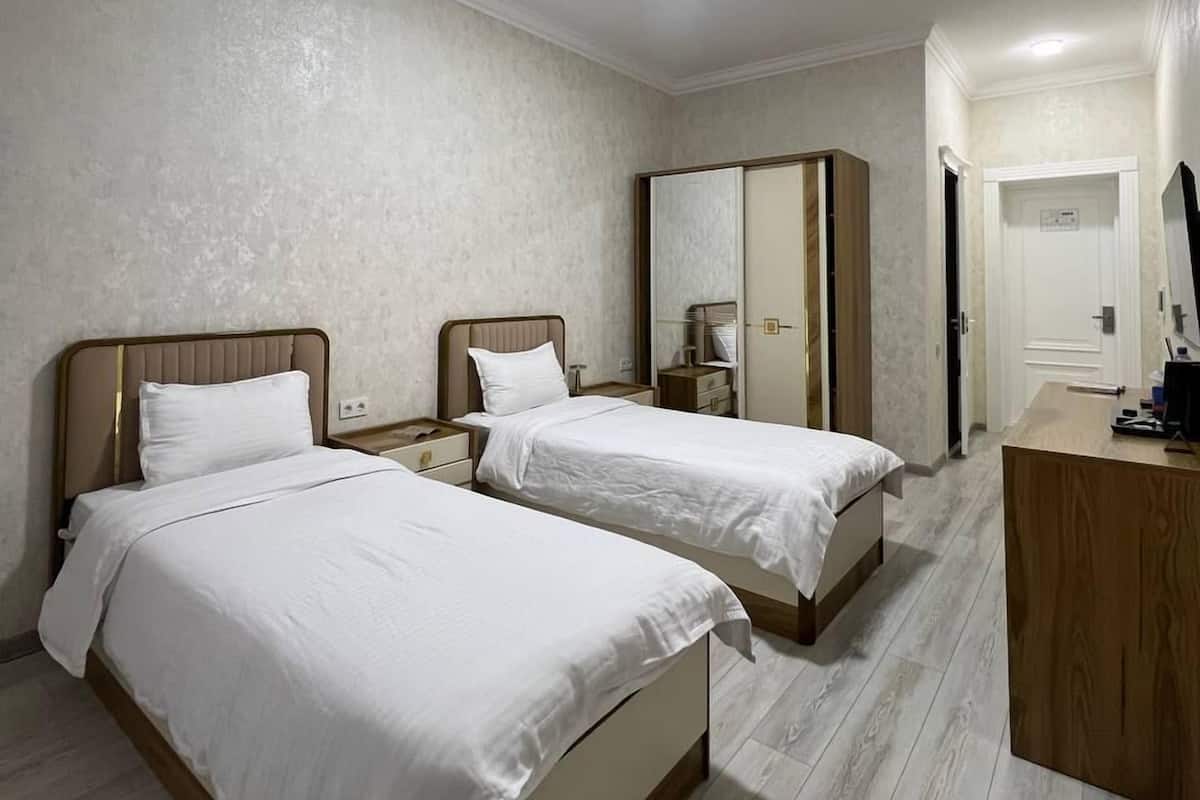 Een hotelkamer met twee bedden, een bureau en een kledingkast.