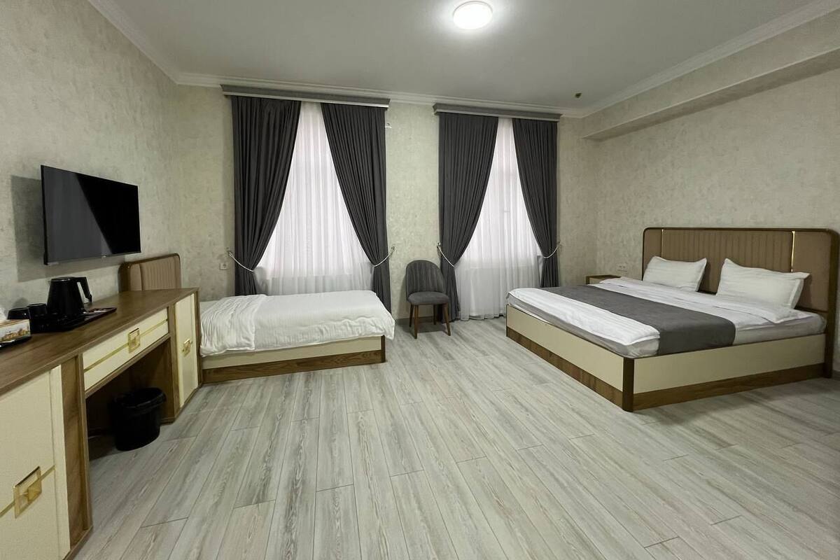 Een hotelkamer met twee bedden, een bureau, een stoel, een televisie en een klein tafeltje.