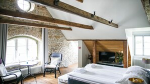 Un dormitorio con cama, televisor, sillón y mesa.