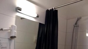 Un baño con lavamanos blanco, espejo, ducha y cortina negra.