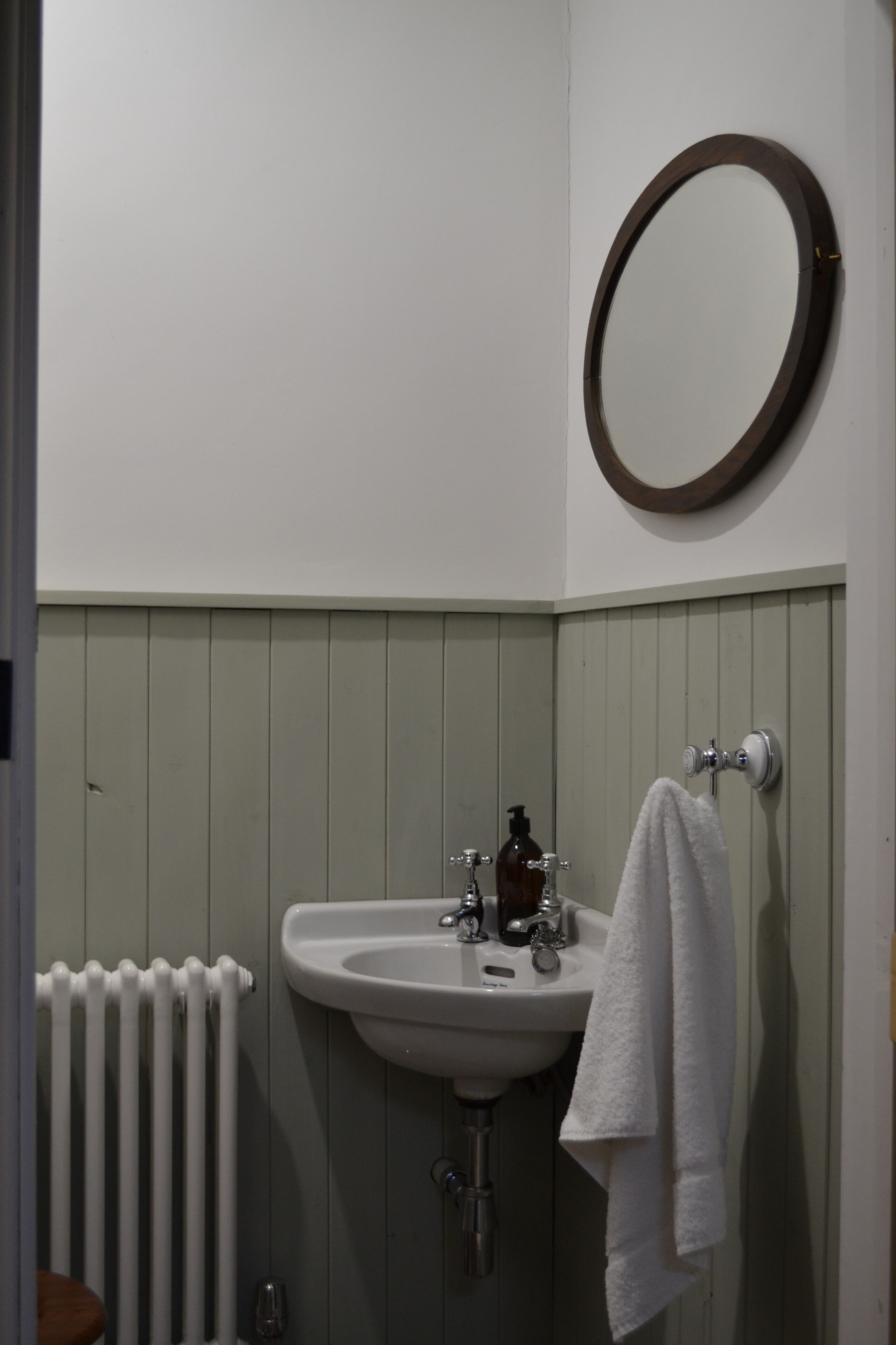 A bathroom with a white sink, a mirror, and a towel hanging on the wall.