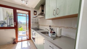 Cuina amb rentaplats, un rentavaixelles, un banyadora i finestra amb vista a un balcó.