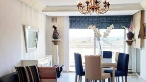 A living room with a sofa, chairs, a chandelier, and a view through a window.