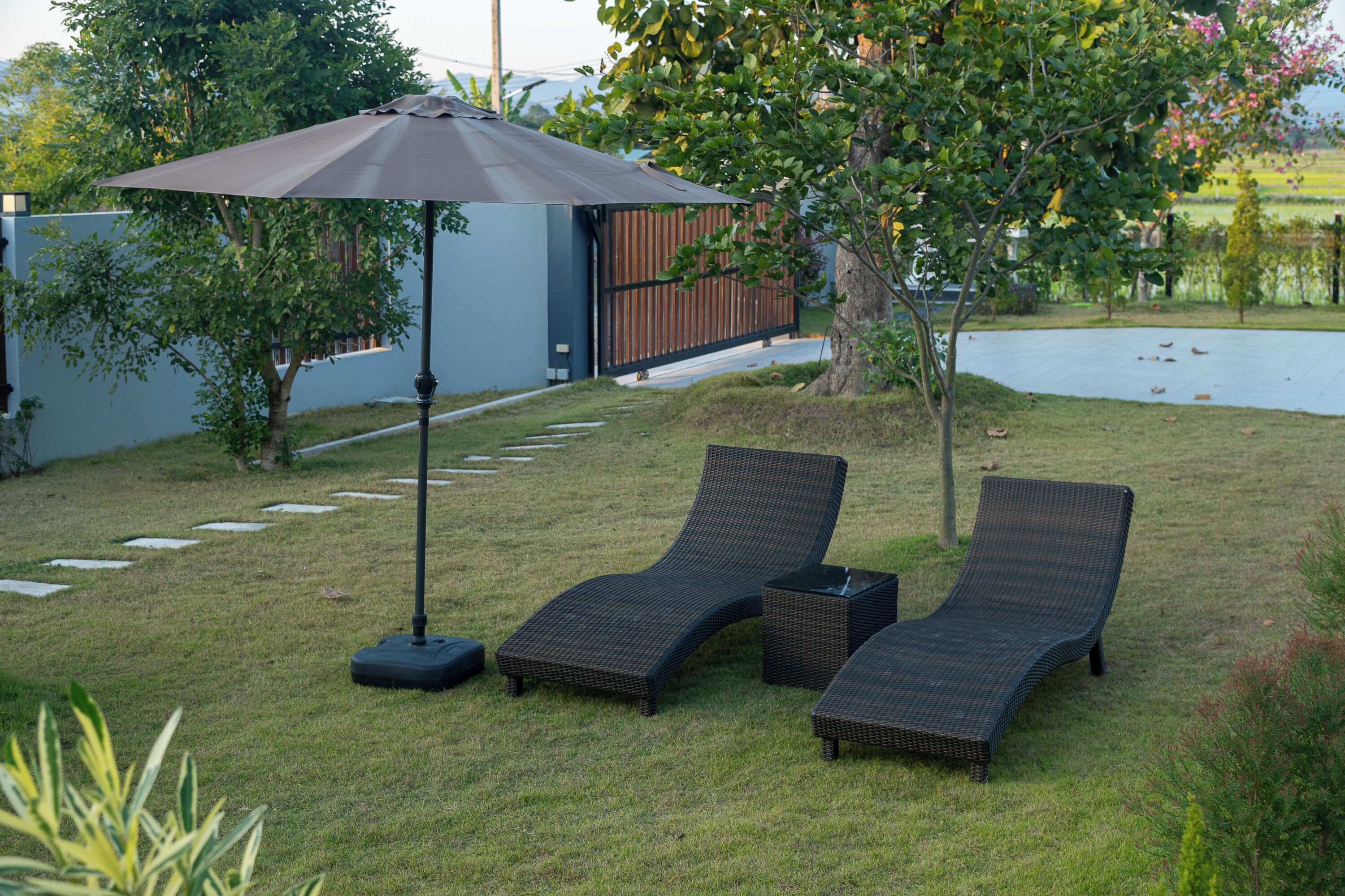 A backyard with two lounge chairs, a patio umbrella, and a small table.