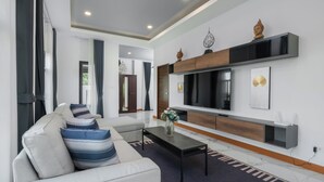Un salon moderne avec un canapé, une table basse et un téléviseur à écran plat fixé au mur.