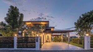Une maison moderne dotée d’une allée couverte, d’une entrée sécurisée par un portail et d’une pelouse bien entretenue.