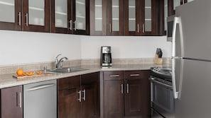 Una cocina con armarios de madera oscura, un refrigerador de acero inoxidable, una cafetera y un lavamanos con salpicadero decorativo.