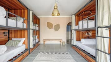 Una habitación con literas, un banco y una alfombra estampada.