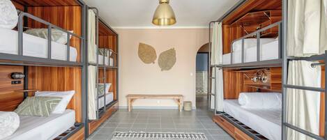 Una habitación con literas, un banco y una alfombra estampada.