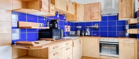 Una cocina moderna con armarios de madera, horno empotrado y salpicadero de azulejos azules.