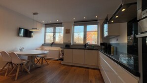 A modern kitchen with a dining area, large windows, and a built-in oven. - Vacation home in the Alter Hof - charming, central, with garden (Bad Zwischenahn)