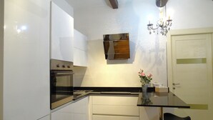 Eine moderne Küche mit weißen Schränken, einer schwarzen Arbeitsplatte und einem eingebauten Backofen. Es ist ein kleiner Tisch mit Stühlen und eine Vase mit Blumen vorhanden.