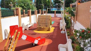 Um parquinho com escorregadores, balanços e uma estrutura para escalar.