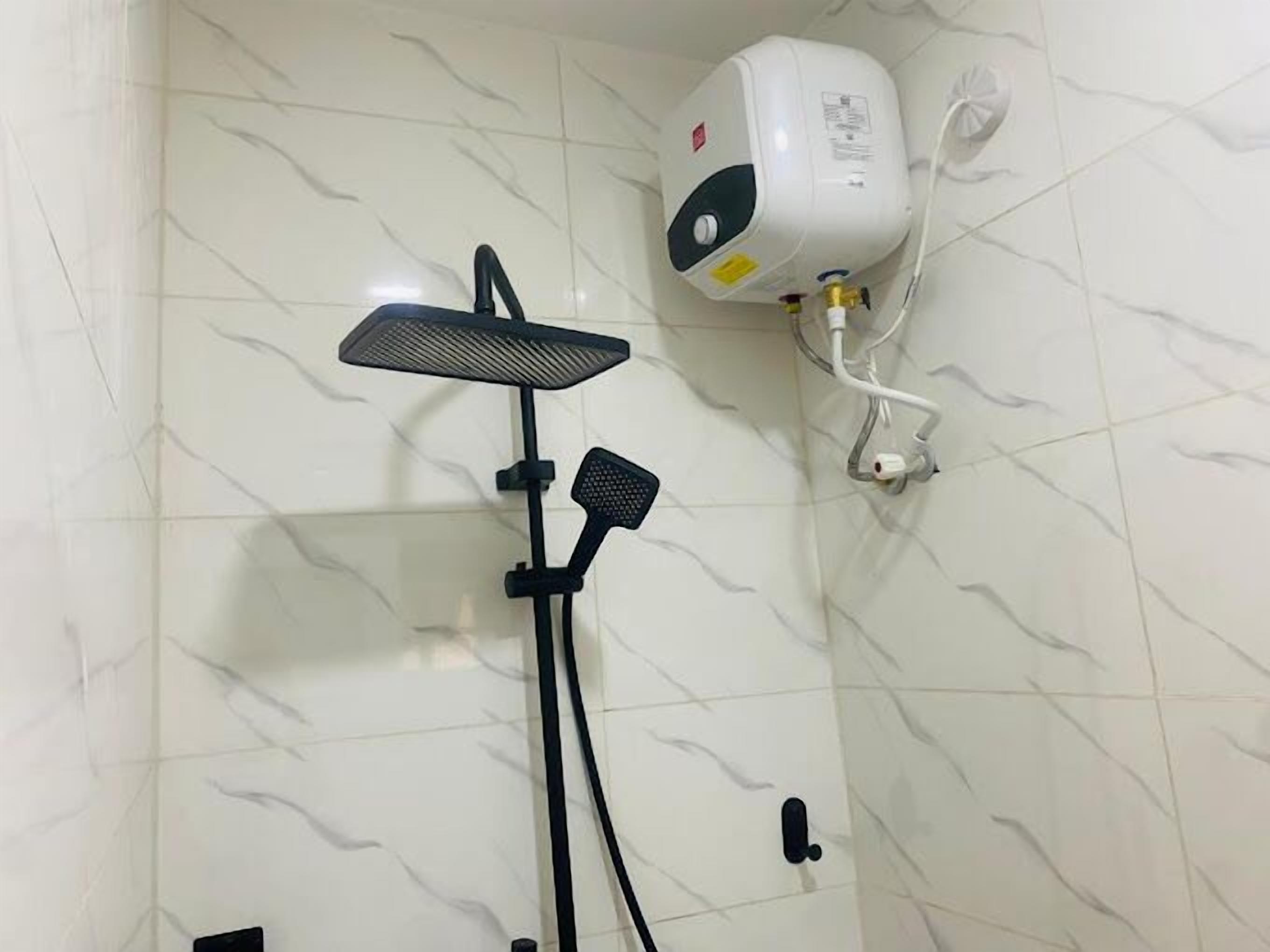 Een douche met een handdouche en een bedieningspaneel aan de muur.