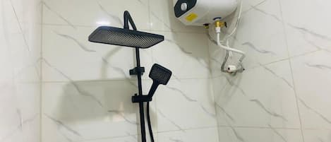 Een douche met een handdouche en een bedieningspaneel aan de muur.