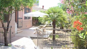 A courtyard with a palm tree, a white umbrella, and a seating area. - Stefy Home (Vaccarizzo-delfino)