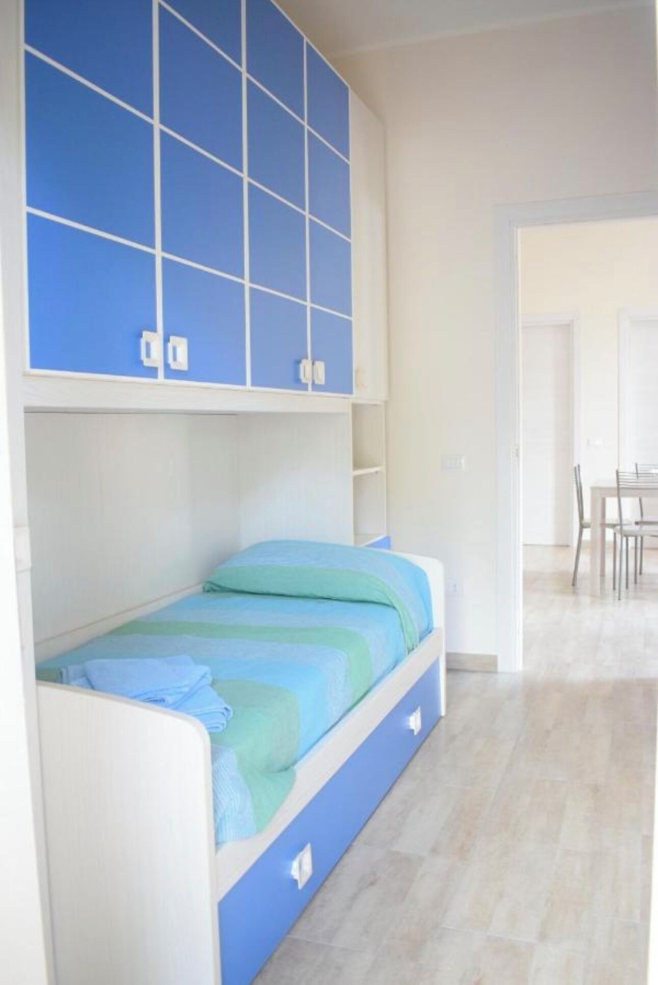 Een slaapkamer met een bed, een blauwe kledingkast en een eethoek.