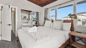 Un dormitorio amplio con una cama grande, techo de madera y vistas al exterior.