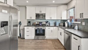 Una cocina moderna con armarios blancos, electrodomésticos de acero inoxidable y encimera de granito.