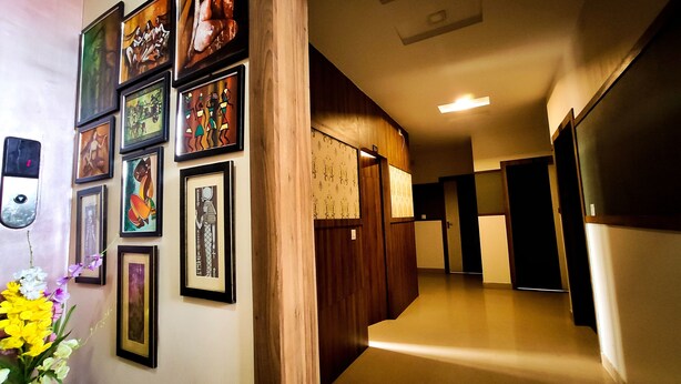 A hallway with framed artwork on the walls, wooden paneling, and a light fixture on the ceiling. - Hotel Spectrum Residency (Guwahati)