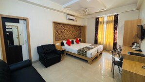 A hotel room with a bed, a black sofa, a desk with a chair, and a television. - Hotel Spectrum Residency (Guwahati)