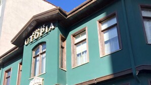 Ein zweistöckiges Gebäude mit grüner Fassade, einer Holztür und mehreren Fenstern.