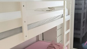 A bunk bed with a pink mattress and a pillow, a white wall, and a window with a view of buildings. - BLUE SEA..... YOUR DREAM VACATION! (Avola)