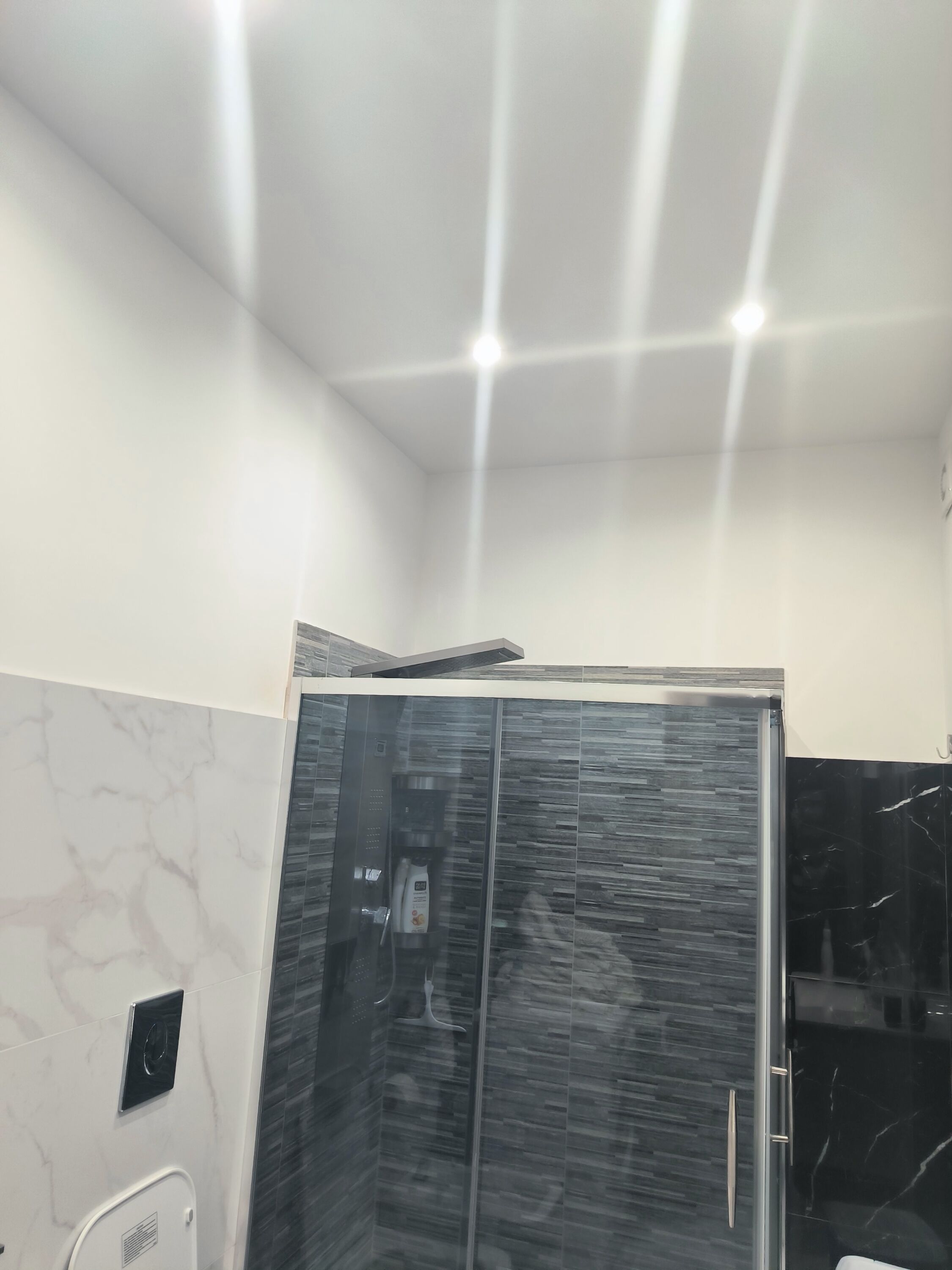 Et stilfuldt badeværelse med glasafskærmet brusebad, marmorvægge og et elegant design.