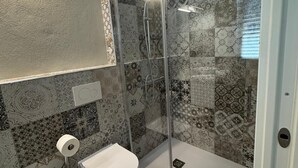 Un baño con ducha envuelta en vidrio, inodoro y lavamanos.
