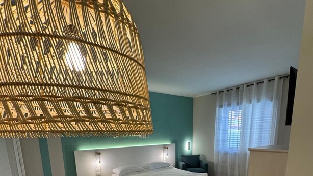 Un dormitorio con cama, mesitas de noche, una lámpara colgante y vistas a la habitación.