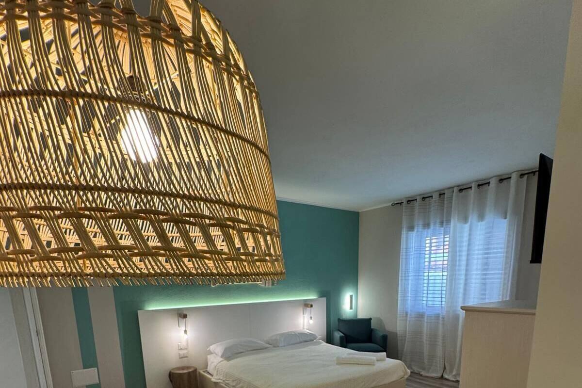 Un dormitorio con cama, mesitas de noche, una lámpara colgante y vistas a la habitación.