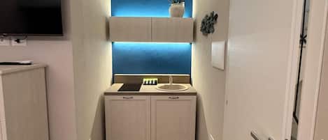A narrow hallway with a built-in vanity, a flat-screen TV mounted on the wall, and a door on the right.
