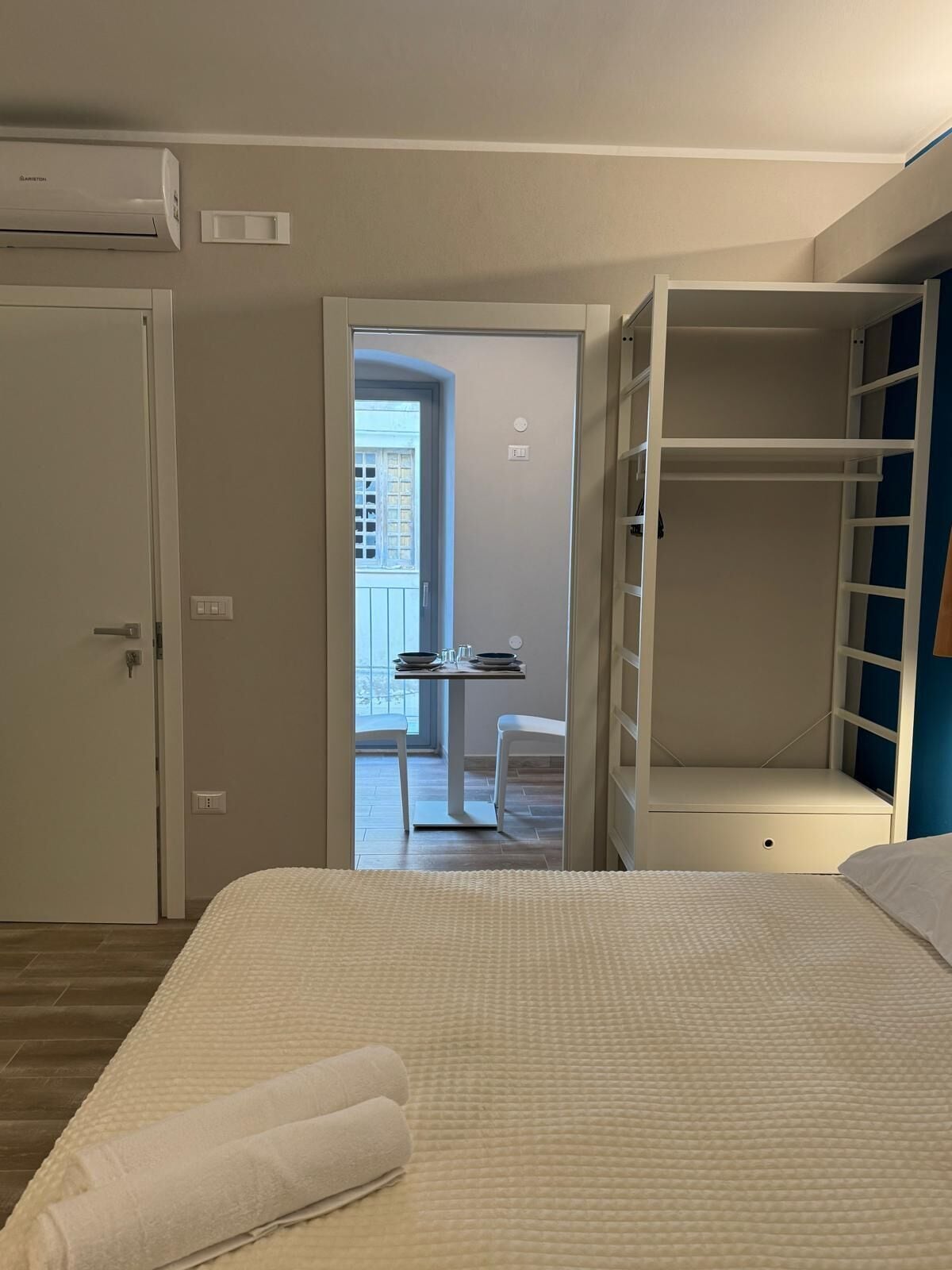 Ein Schlafzimmer mit Bett, Kleiderschrank und Blick auf einen Balkon.