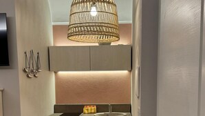 Una cocina moderna con una isla central, iluminación colgante y un comedor con una silla blanca.