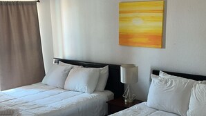 Ein Hotelzimmer mit zwei Betten, weißer Bettwäsche, einem Nachttisch mit Lampe und einem Bild an der Wand.