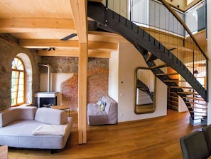 Une pièce de style loft avec des murs en briques apparentes, un plafond en bois, un escalier et un canapé.
