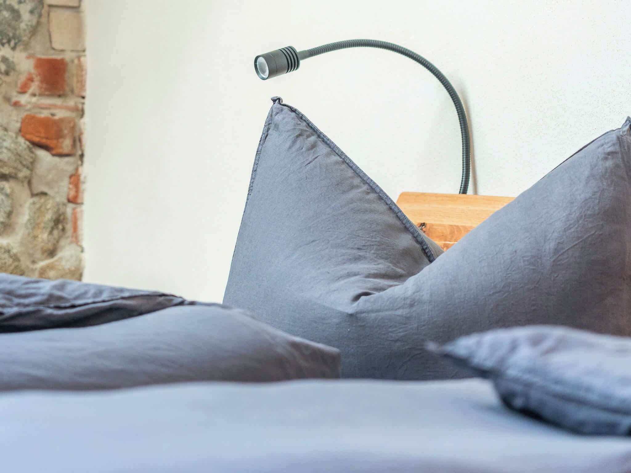 A bed with gray pillows and a black lamp.
