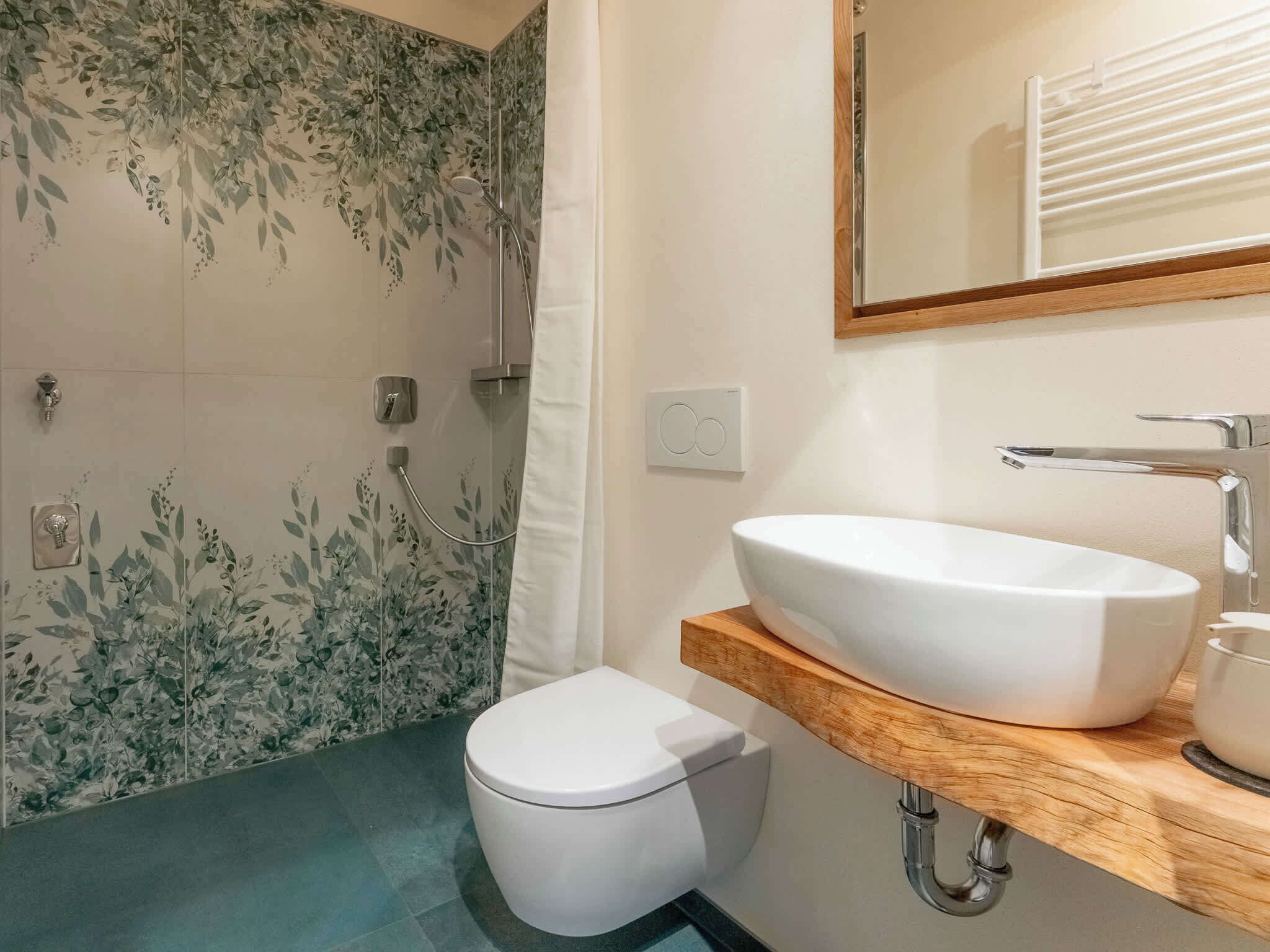 Een badkamer met een douche, toilet en wastafel.