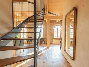 Un escalier en colimaçon avec des marches en bois et des rampes en métal, menant à l’étage supérieur.