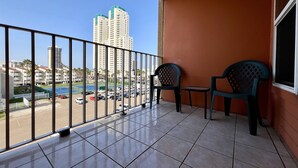 Ein Balkon mit Fliesenboden, zwei Stühlen und einem Geländer.
