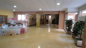 Eine großzügige Lobby mit poliertem Boden, einer zentralen Zierbrunnen und Kübelpflanzen.