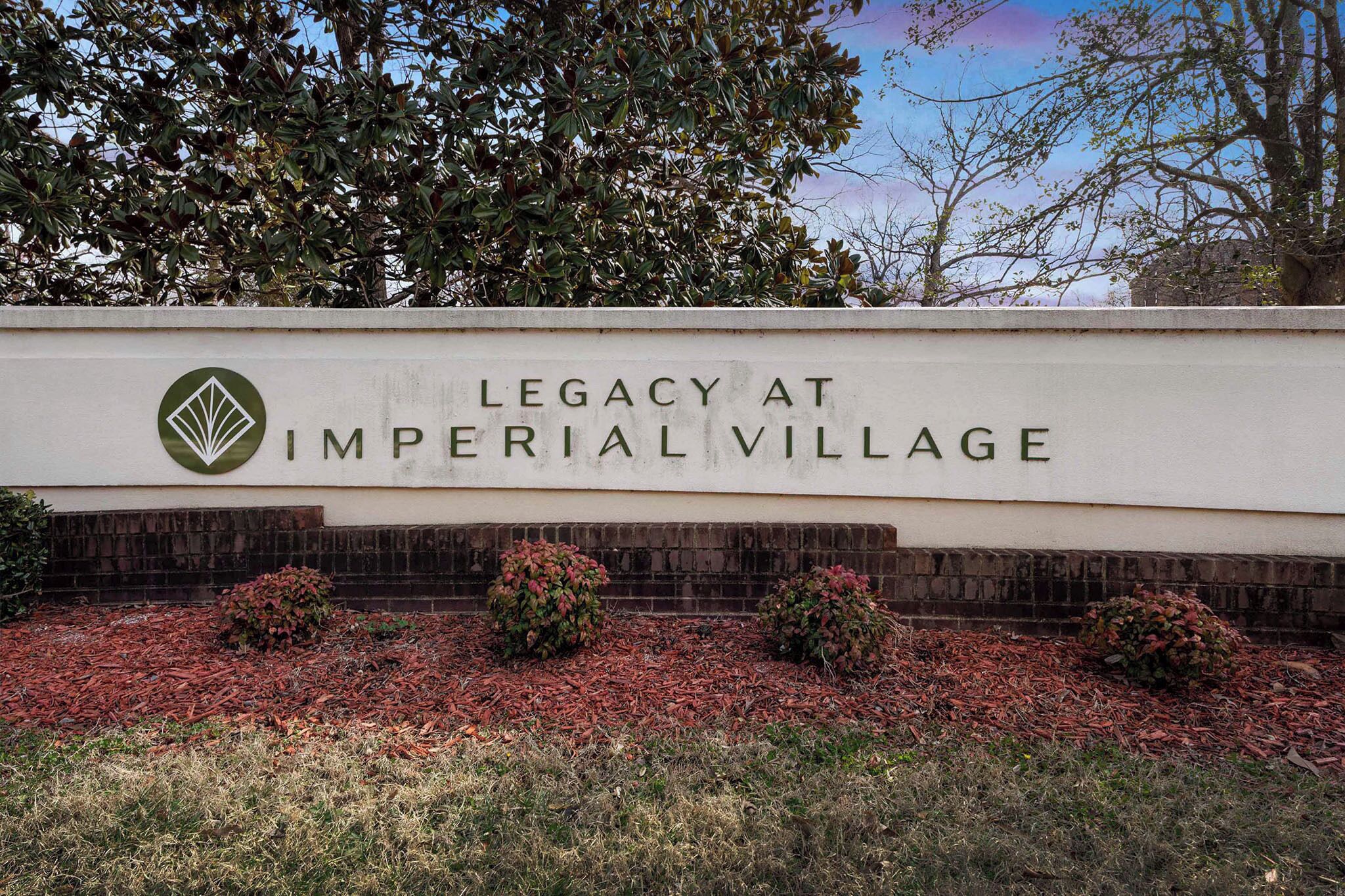 A sign for "Legacy at Imperial Village" with a logo, text, and landscaping.